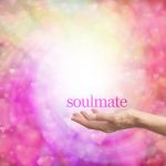 A hand extended, holding the word, Soulmate, set to a cosmic pink and orange background
